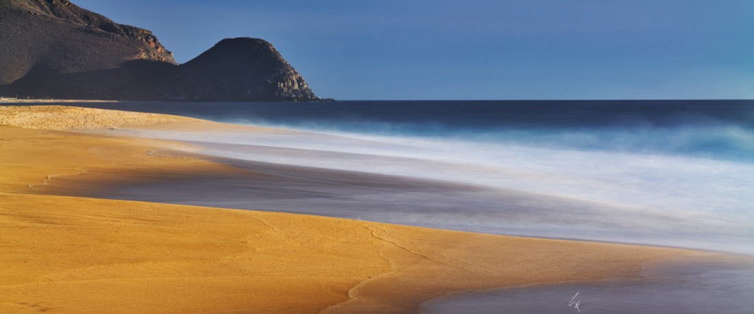 Larga exposición del oleaje en una playa de Los Cabos, con el cerro al fondo